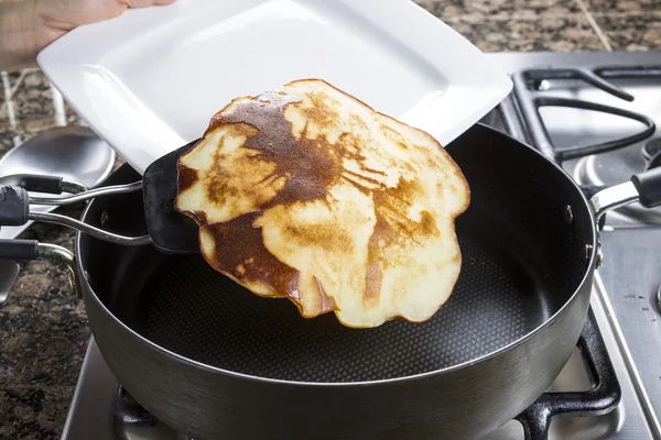 Golden Brown Pancake being placed onto White Plate — Stock Photo, Image
