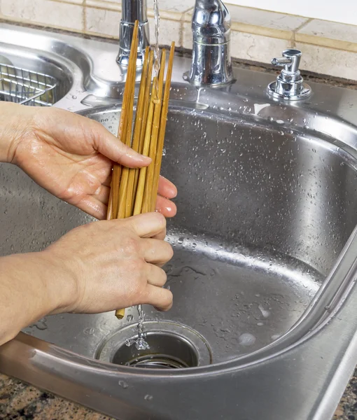 Женские руки смывают бамбуковые палочки для еды — стоковое фото
