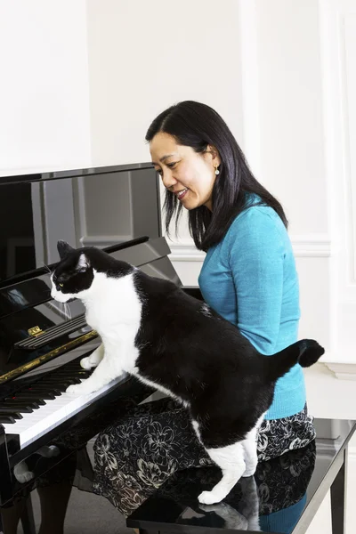 Donna matura e il suo gatto fianco a fianco al pianoforte — Foto Stock