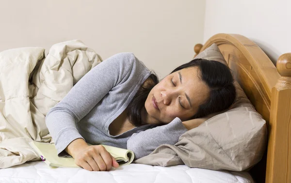 Reife Frau schläft mit Buch neben sich ein — Stockfoto