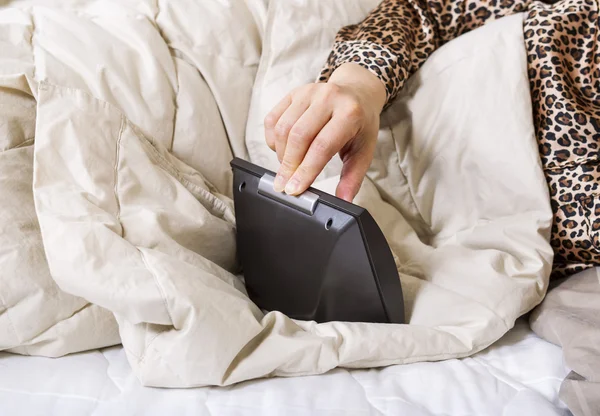 Mano femenina apagando el despertador mientras está en la cama —  Fotos de Stock
