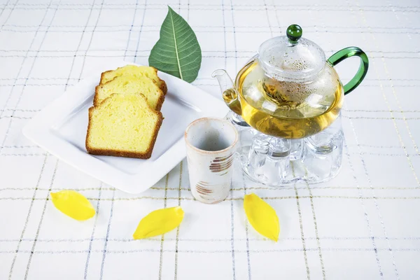 Té verde y pastel en la mesa con hojas de flores —  Fotos de Stock