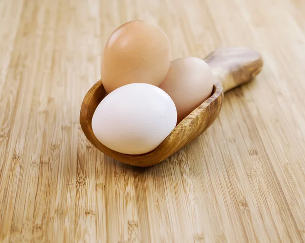Целые органические яйца в деревянной ложке — стоковое фото
