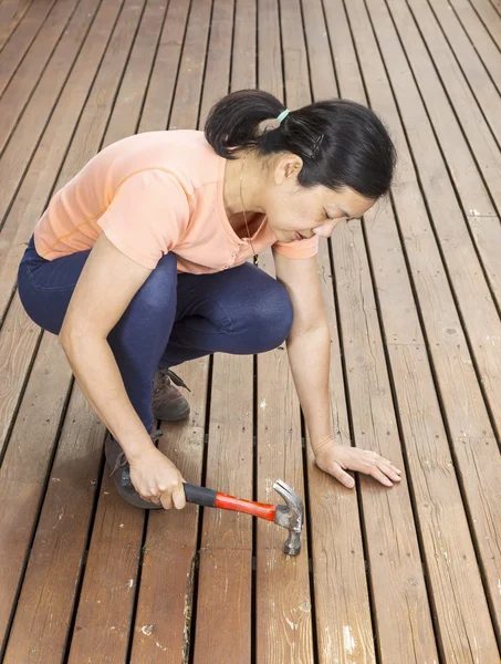 Mature woman working on Deck with Hammer — Stock Photo, Image