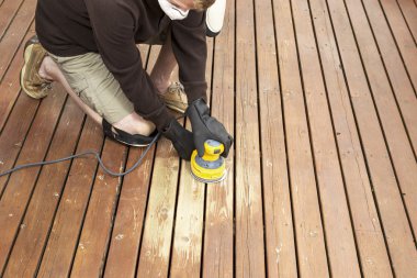 Mature man performing maintenance on home wooden deck