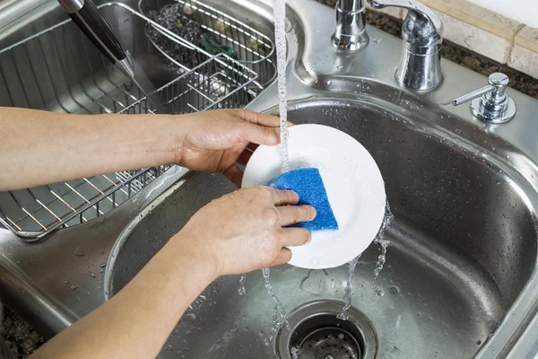 Female hands washing single white dinner plate — Stock Photo, Image