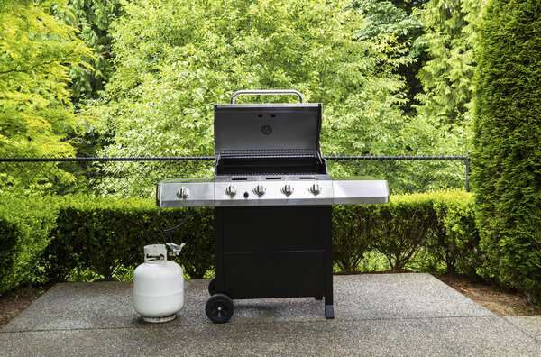 Outdoor cooker with lid in open position on home patio