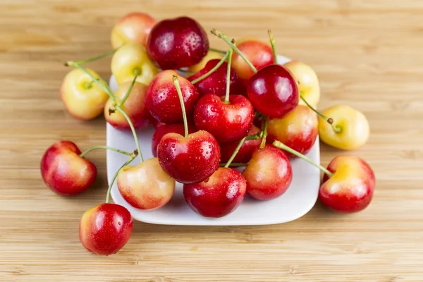 Cerises jaunes et rouges en plaque blanche — Photo