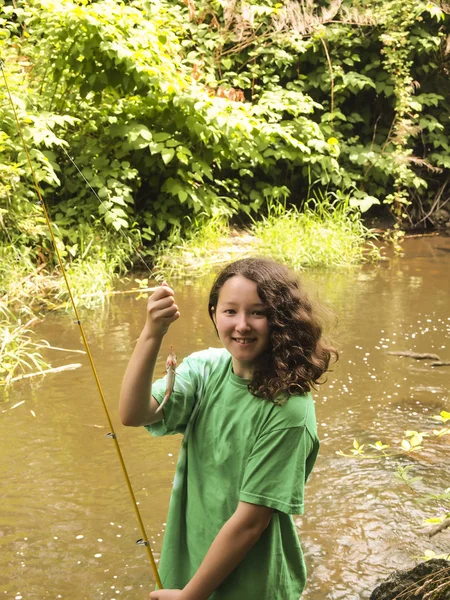 Very happy young girl catches small trout — Stock Photo, Image