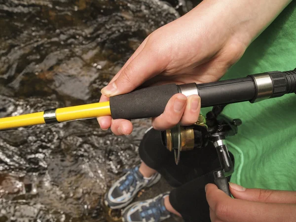 Female hands holding fishing reel while fishing in small stream — Stock Photo, Image