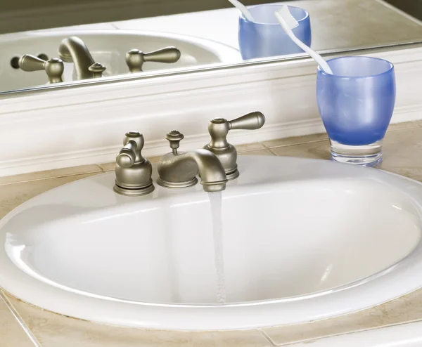Fregadero y grifo de baño blanco en posición abierta con agua limpia —  Fotos de Stock