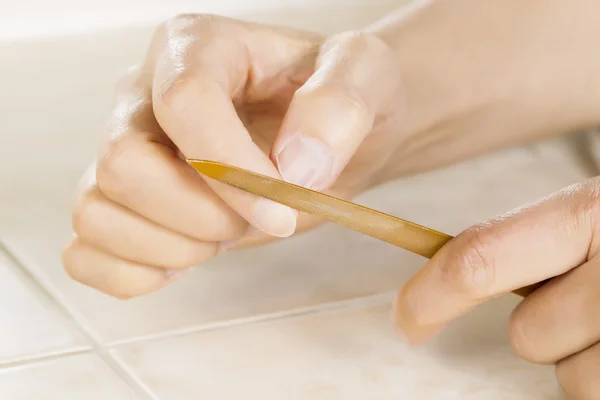 Vrouwelijke handen met behulp van gouden metalen nagelvijl — Stockfoto