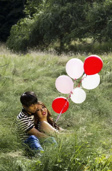 Lovers with their balloons resting in Tall Green Grass Field — Stock Photo, Image
