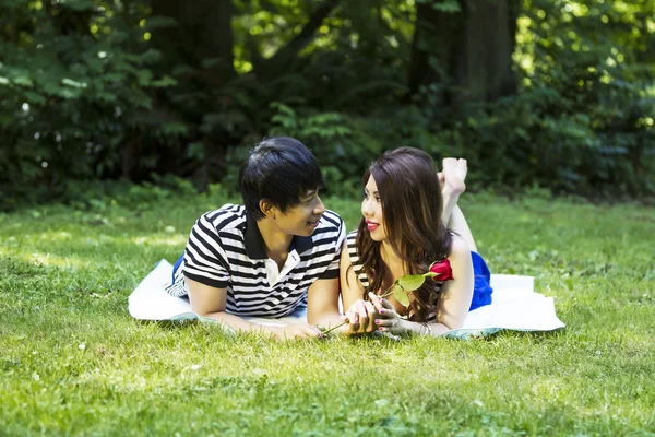 Pareja de jóvenes adultos compartiendo su amor mientras yacen en una manta O — Foto de Stock