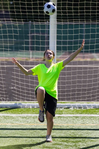 Chica joven mirando hacia arriba en la pelota de fútbol entrante — Foto de Stock