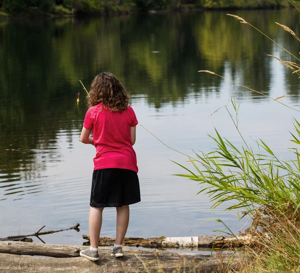 Jong meisje op zoek waar te vissen op meer — Stockfoto