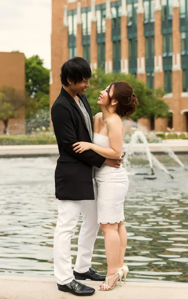 Pareja de jóvenes adultos abrazándose frente a la fuente de agua — Foto de Stock