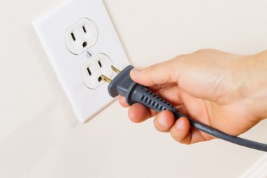 Inserting Power Cord Receptacle in wall outlet clipart