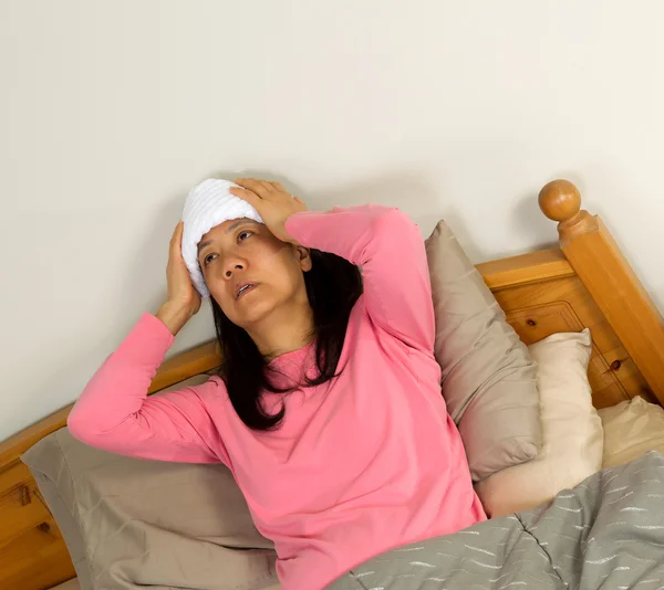 Volwassen vrouw behandelen koorts in bed — Stockfoto