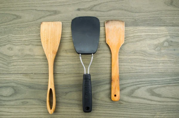 Kitchen spatulas on aged wood — Stock Photo, Image