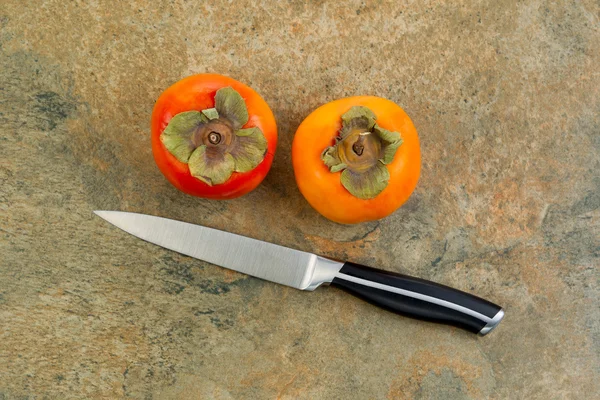 Persimmons with Paring Knife on Natural Stone Counter Top — Stock Photo, Image