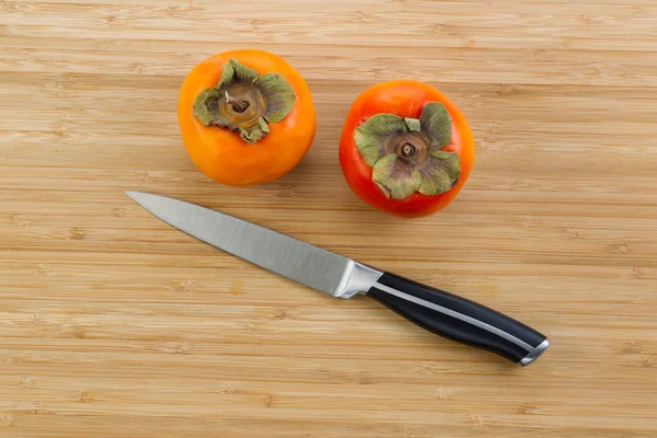 Persimmons com faca de paring em madeira de bambu natural — Fotografia de Stock