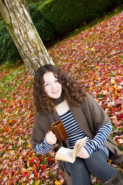 Joven adolescente afuera leyendo un libro durante la temporada de otoño —  Fotos de Stock