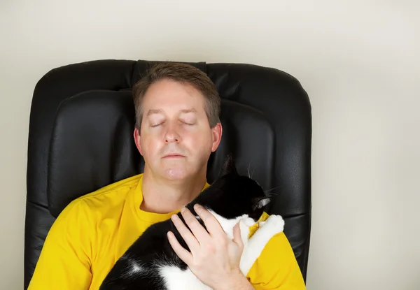 Зрілий чоловік і його сімейний кіт розслабляється в масажному кріслі — стокове фото