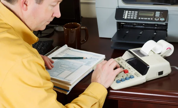 Mature man working the numbers on his income taxes — Stock Photo, Image