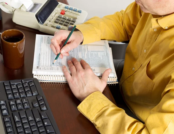 Hombre maduro poniendo información en tablas de impuestos — Foto de Stock