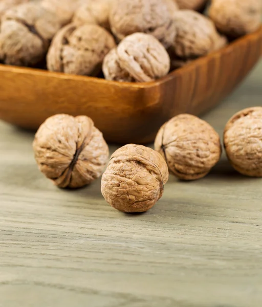 Целые грецкие орехи внутри оболочки на выцветшем дереве — стоковое фото