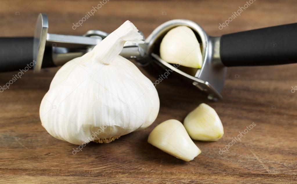 Fresh Garlic with Press on Wooden Board 