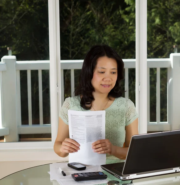 Mujer madura que trabaja en casa con formularios fiscales — Foto de Stock