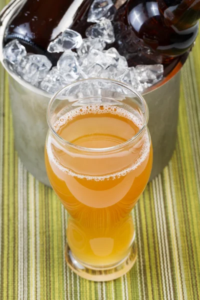 Freshly poured beer with extra bottles on ice in bucket — Stock Photo, Image