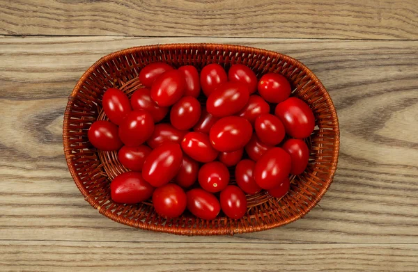 Mandje van verse druiven tomaten op leeftijd hout — Stockfoto