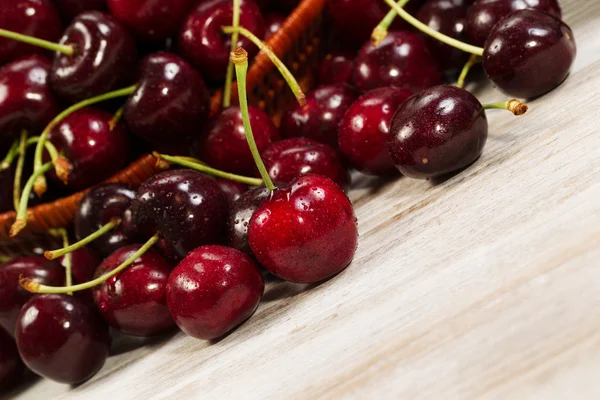 Vue en angle de cerises noires mûres posées devant le panier sur — Photo