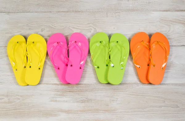 Four pairs of New Sandals on faded white wood — Stock Photo, Image