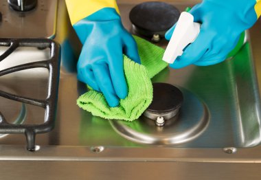 Gloved Hands Cleaning Stove Top Range with Spray bottle and Micr clipart