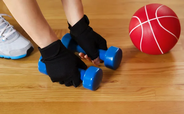 Mujer haciendo ejercicio con pesos pequeños en el suelo de madera gimnasio — Foto de Stock