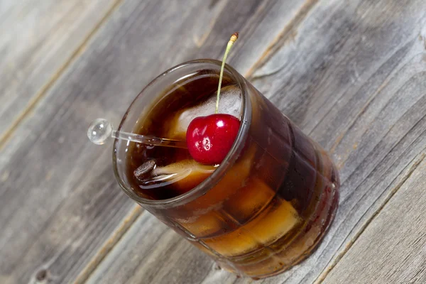 Cola und Rum mit reifer Kirsche und Eis im Glas — Stockfoto