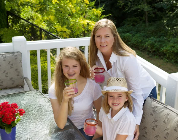 Mother and her daughters drinking grapefruit juice while outdoor — Stock Photo, Image