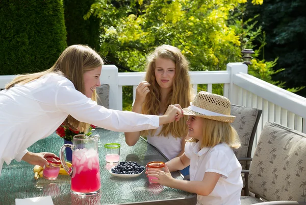 Madre mettere cappello sulla figlia più giovane durante la colazione all'aperto — Foto Stock