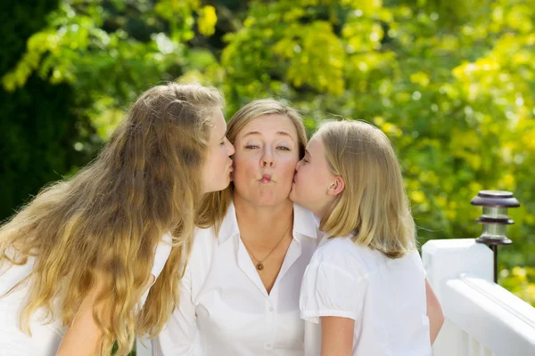 Happy mother and her daughters sharing a kiss outdoors — Stock Photo, Image