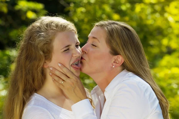 Adolescente filha não feliz de sua mãe beijá-la — Fotografia de Stock