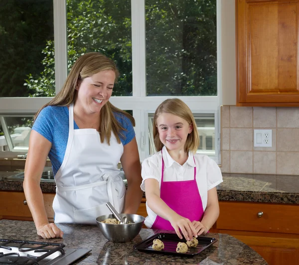 Mother teaching her daughter how to make cookies from raw dough — Stock Photo, Image