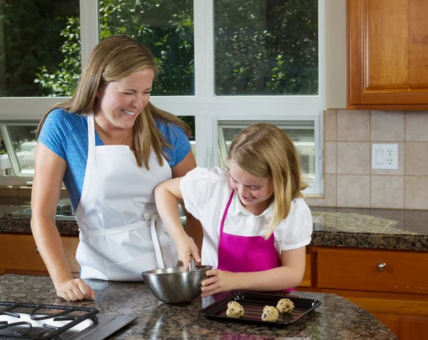 Madre cuidando a su hija joven sobre cómo hacer galletas —  Fotos de Stock