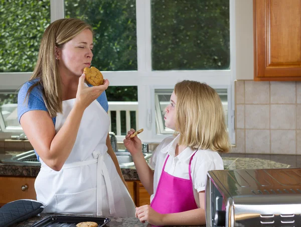 Mamá e hija disfrutando de galletas recién horneadas en la cocina —  Fotos de Stock