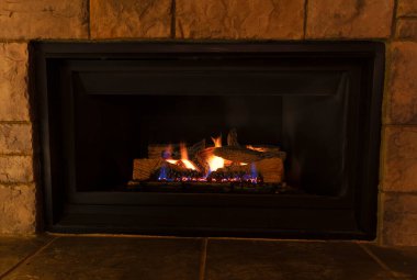 Burning natural gas fireplace during the evening at home  clipart