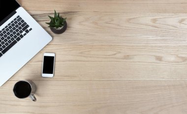 Laptop bilgisayarı, akıllı telefon, iş ve okul için bebek bitkisi ve kahve içeceği olan meşe ağacından ofis masası. Düz konum biçiminde kopyalama alanı olan üst görünüm. 