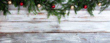 Noel ya da yeni yıl tatili için beyaz rustik ahşap üzerine altın ve kırmızı top süsleri olan gerçek köknar dalları  